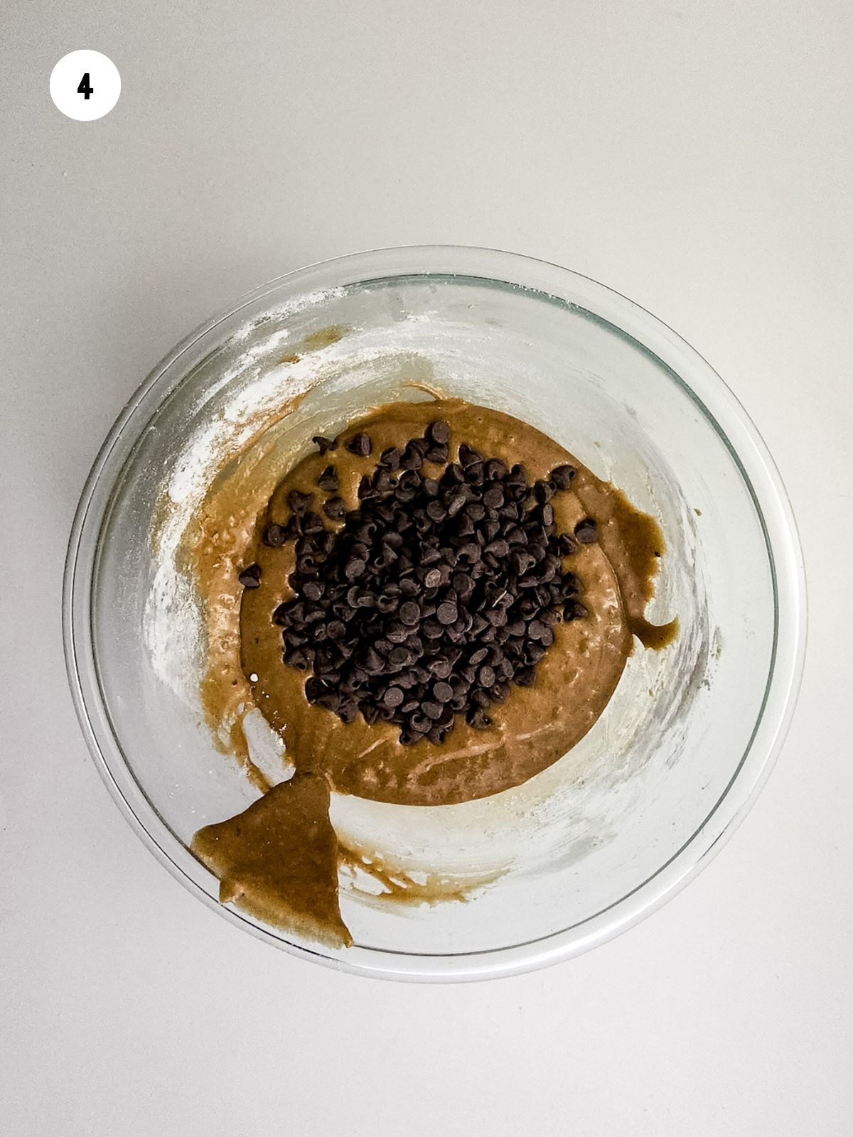 chocolate chips added to cookie batter in bowl. 
