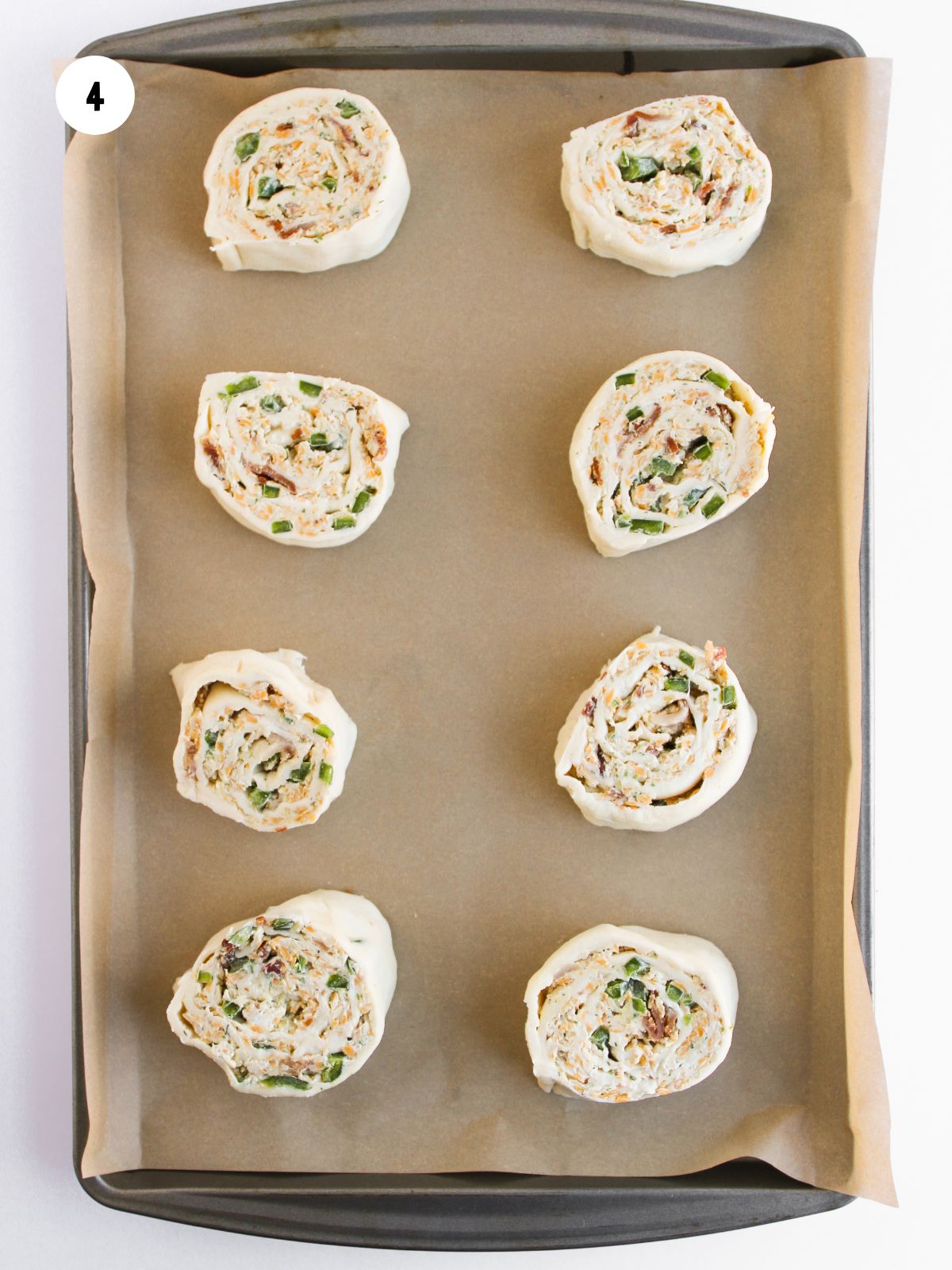 jalapeno popper pinwheel slices on a parchment lined baking sheet