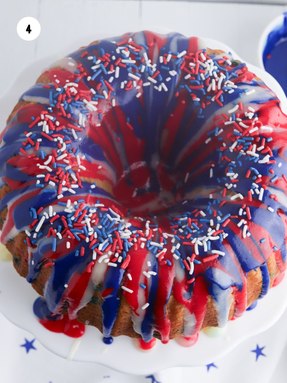 Overhead view of red white and blue frosting drizzled over the bundt cake and topped with red white and blue sprinkles.