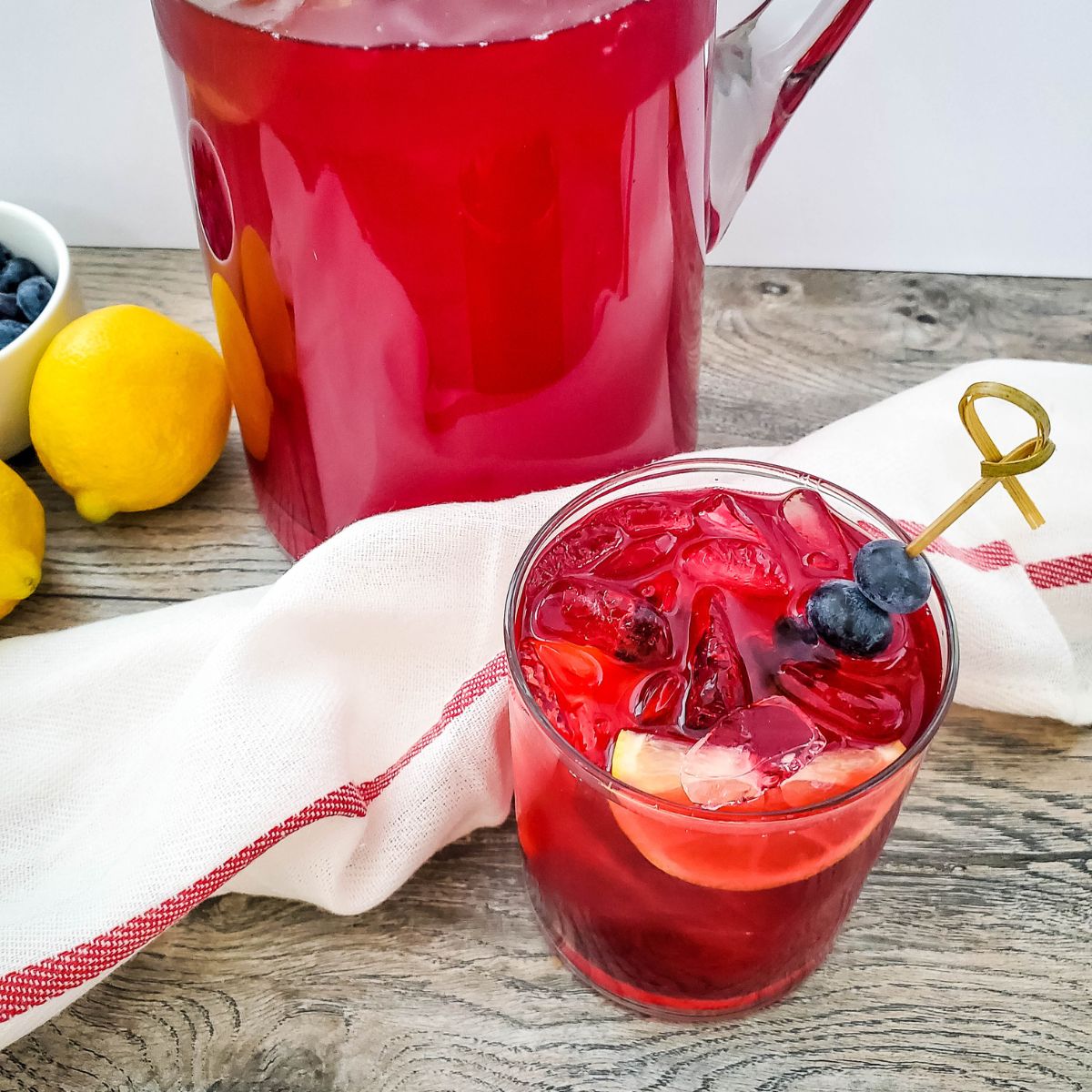 Blueberry Lemonade served in a glass with a wedge of lemon and a skewer of blueberries