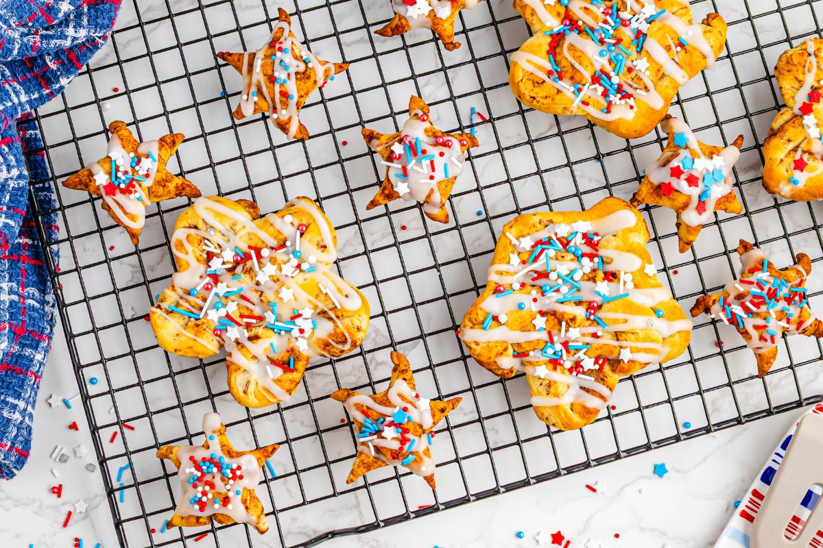 different sized star shaped cinnamon rolls on baking rack decorated for July 4th.