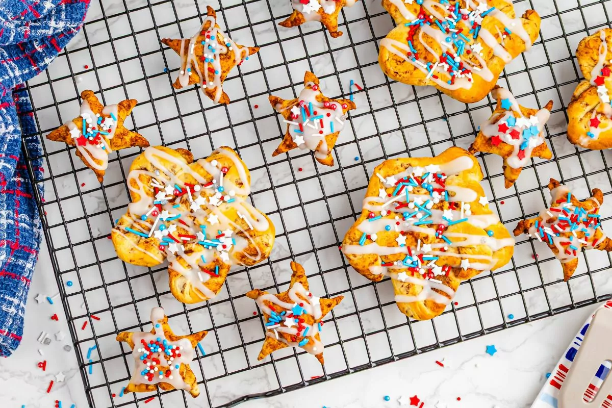 different sized star shaped cinnamon rolls on baking rack decorated for July 4th.