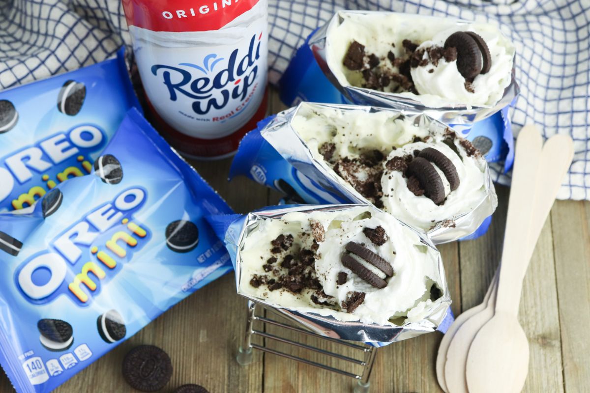 Walking Oreo Desserts with bags of mini oreos, can of Redii Whip, and wood spoons