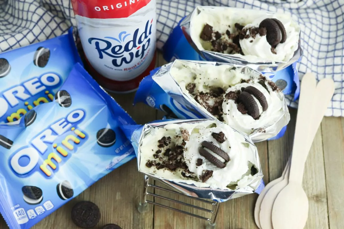 Walking Oreo Desserts with bags of mini oreos, can of Redii Whip, and wood spoons