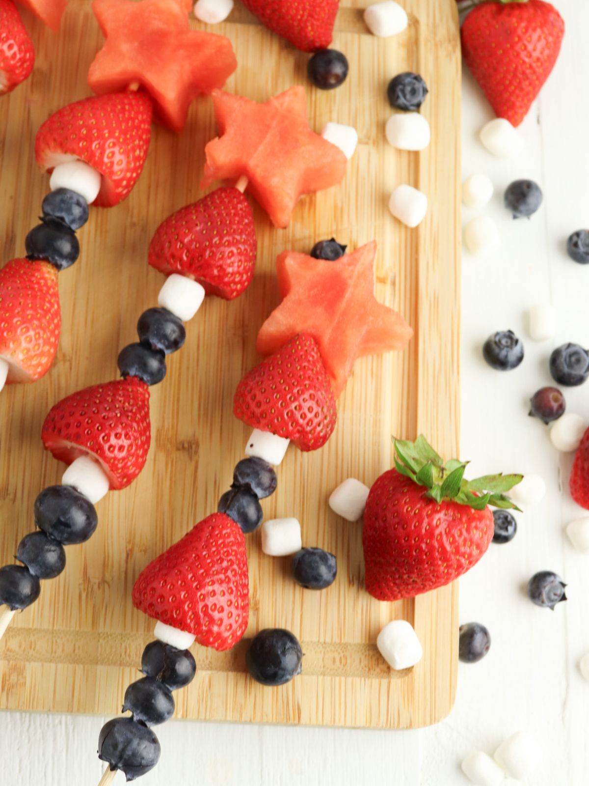 Fruit Kabobs stacked with 3 blueberries, 1 mini marshmallow, 1 strawberry, 2 blueberries, 1 mini marshmallow, 1 strawberry, then topped with a star shaped watermelon.