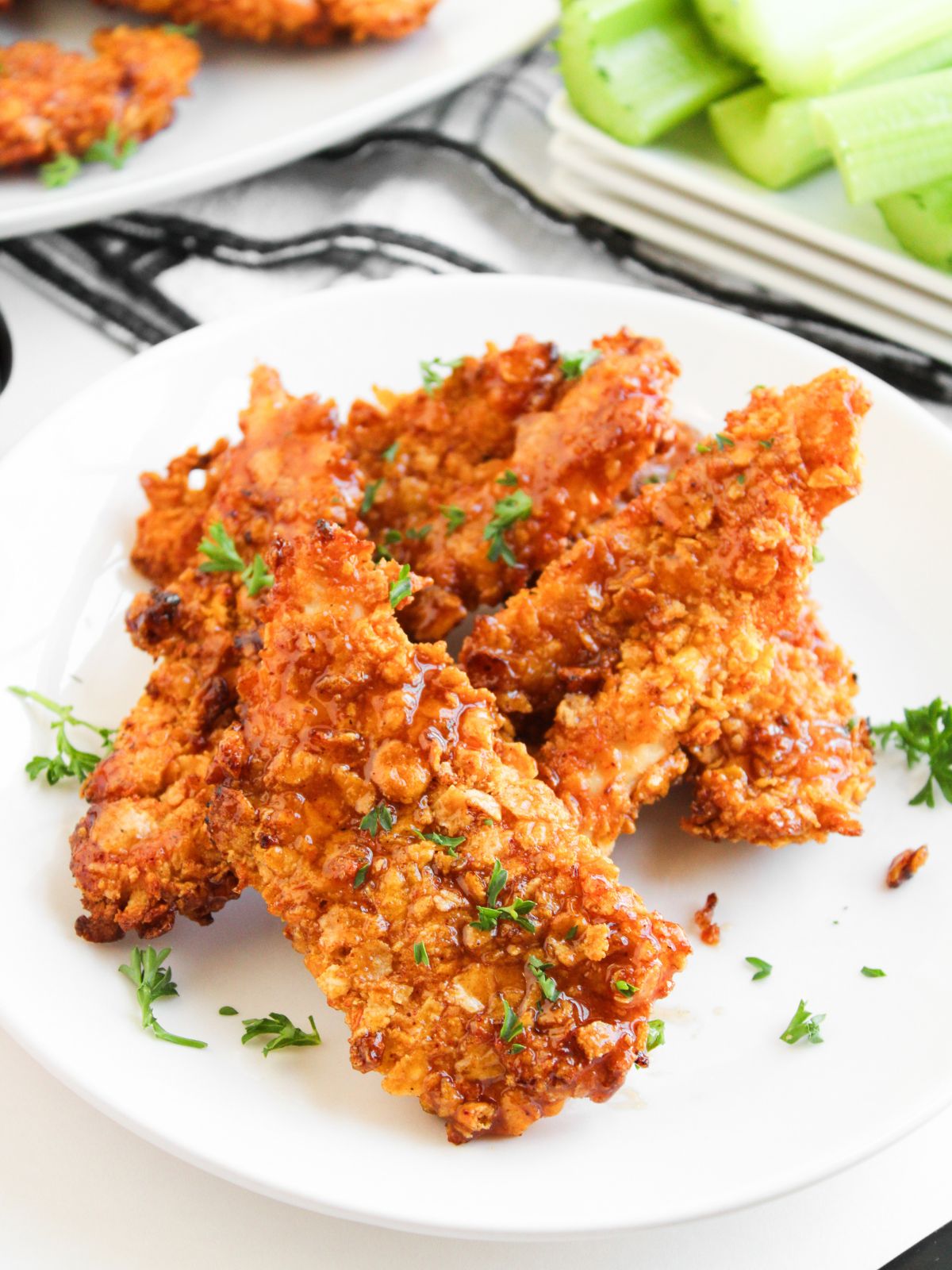 Honey BBQ Air Fryer Chicken Tenders served on a white plate with celery in the background.