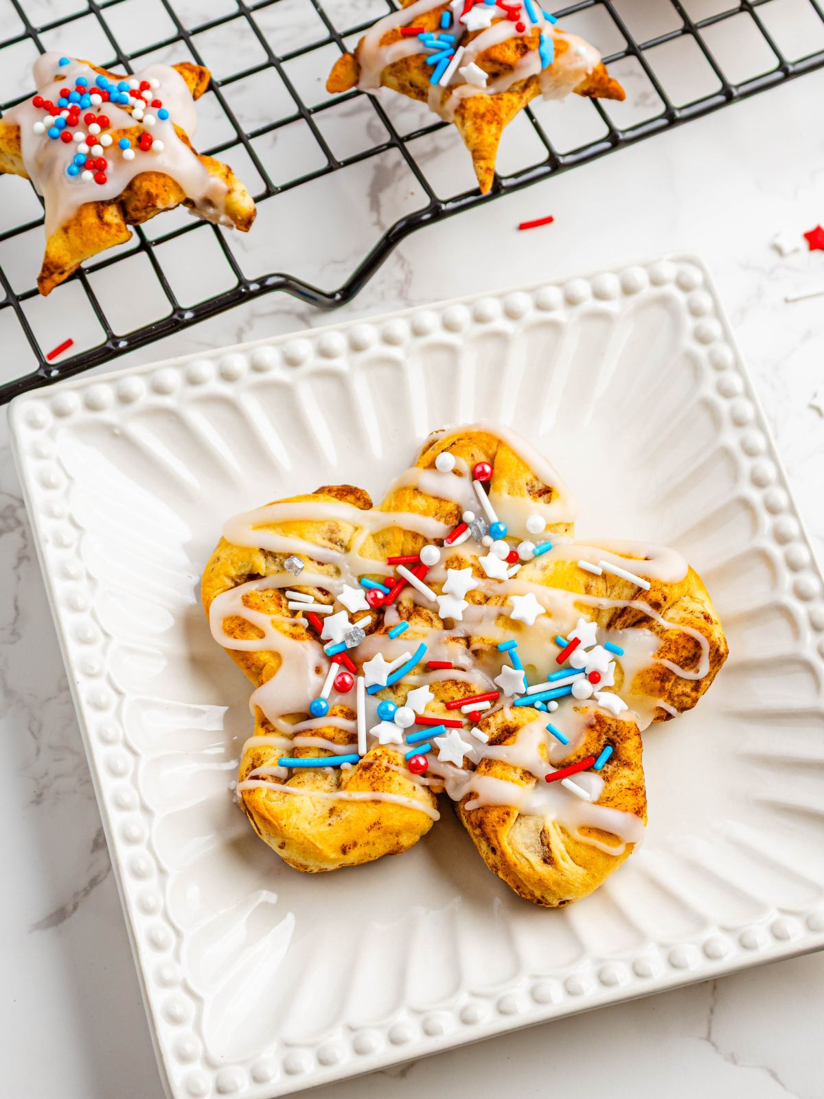 large cinnamon roll on white plate decorated for patriotic holidays.