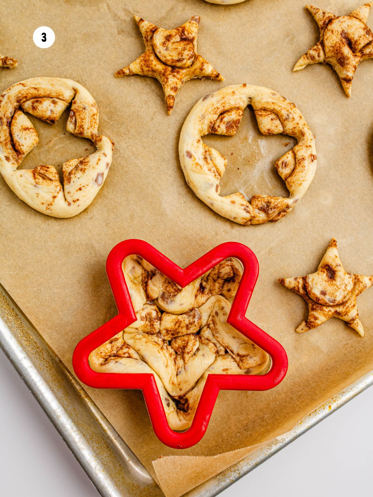 large red star cookie cutter on top of unbaked cinnamon roll.