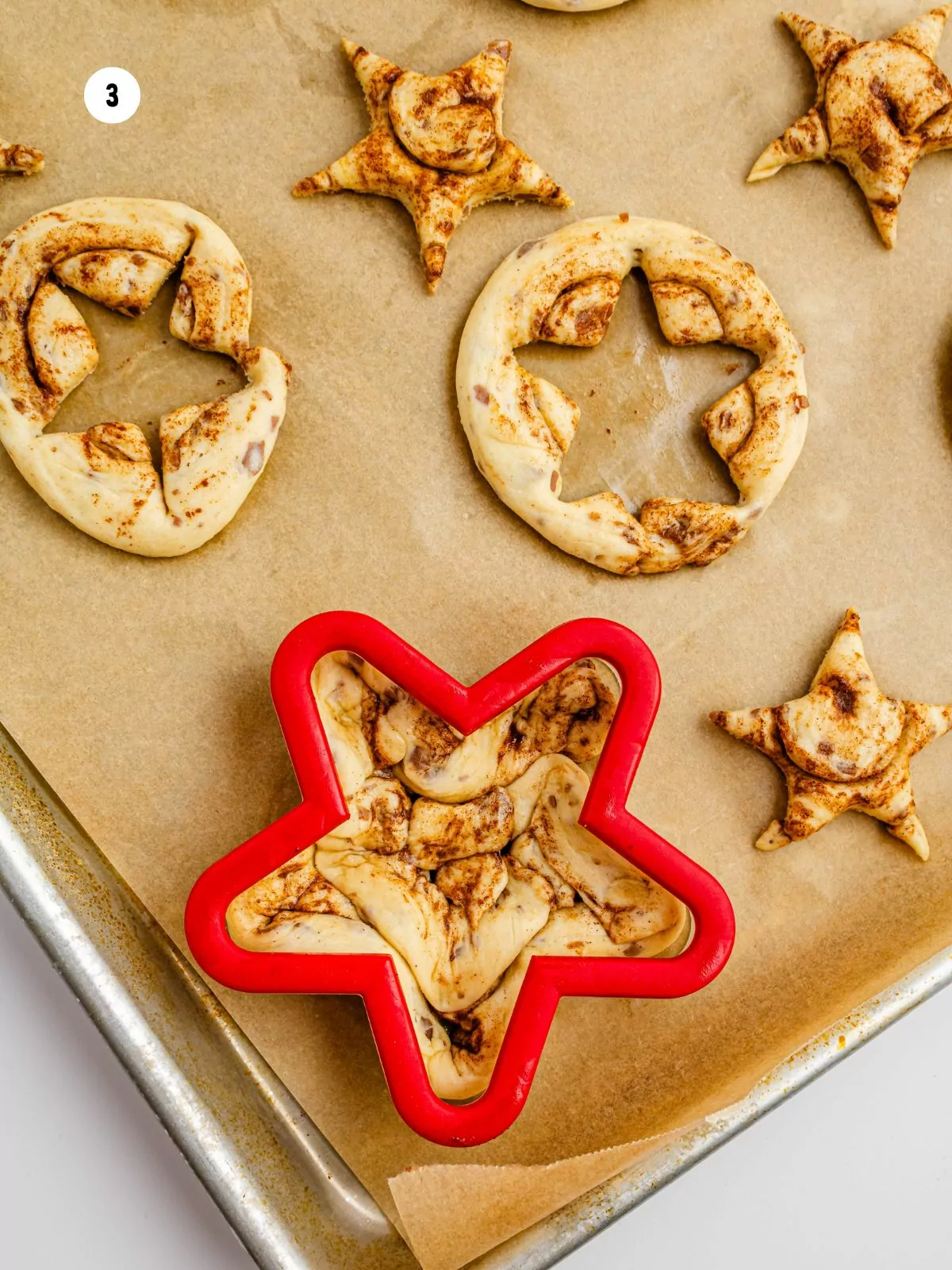 large red star cookie cutter on top of unbaked cinnamon roll.