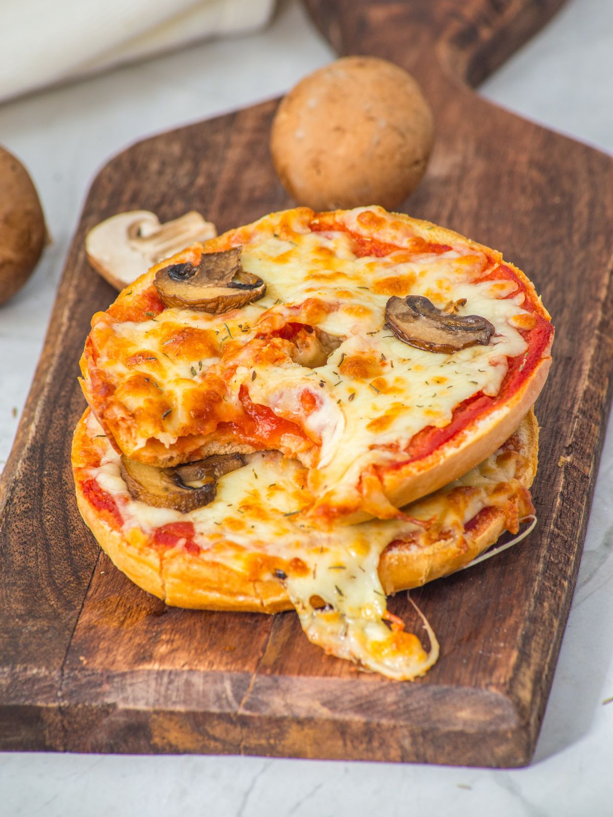 Bagel mushroom pizzas with a bite taken out.