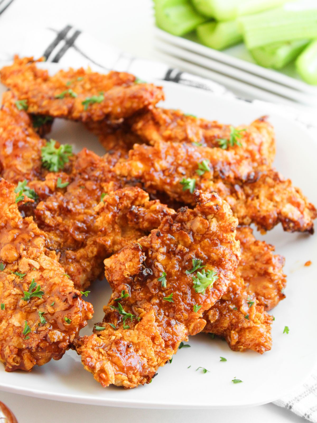 Plate of air fried chicken tenders coated in honey bbq sauce.