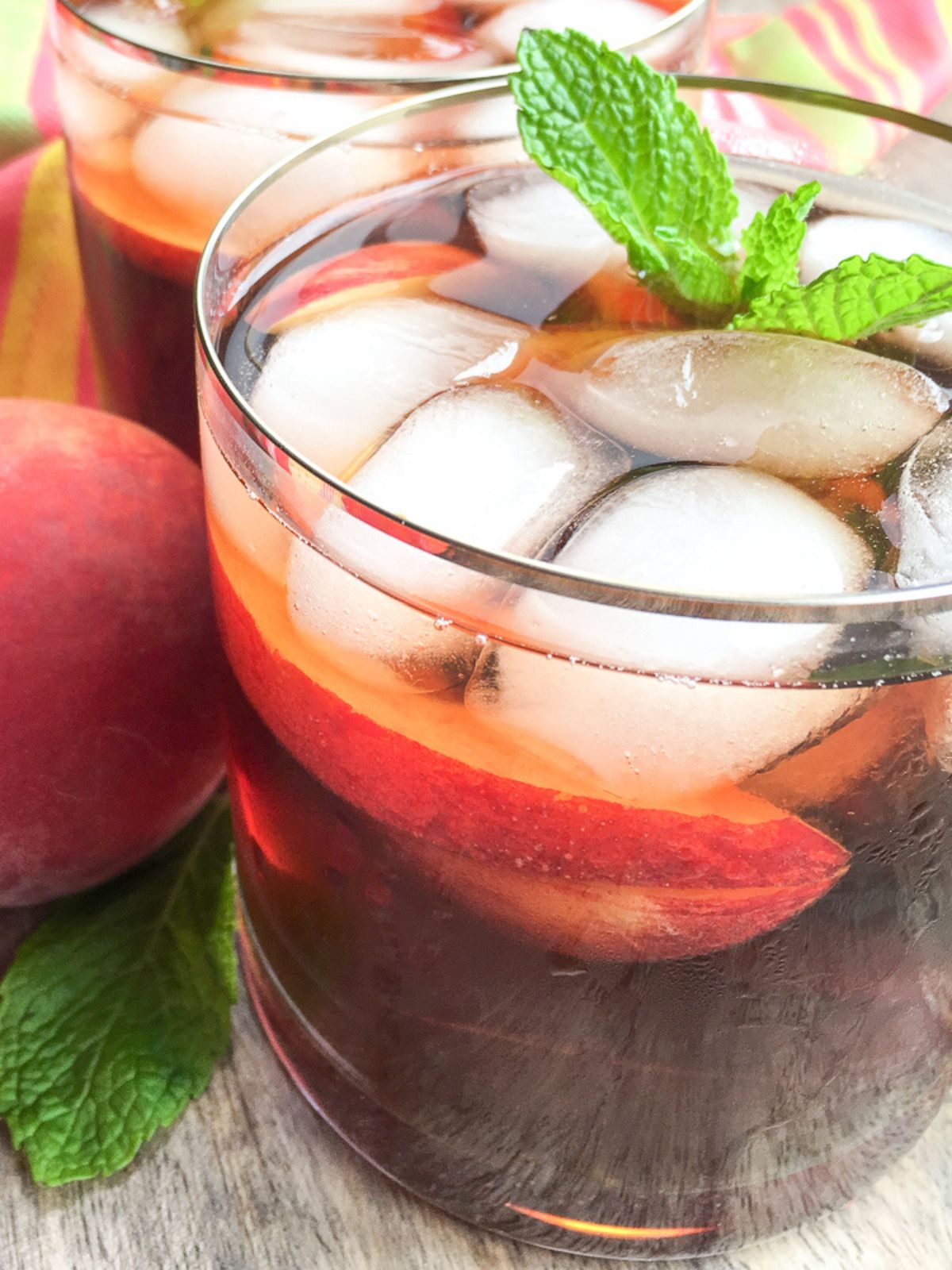 two glasses of iced tea made with fresh peaches, mint and ginger.