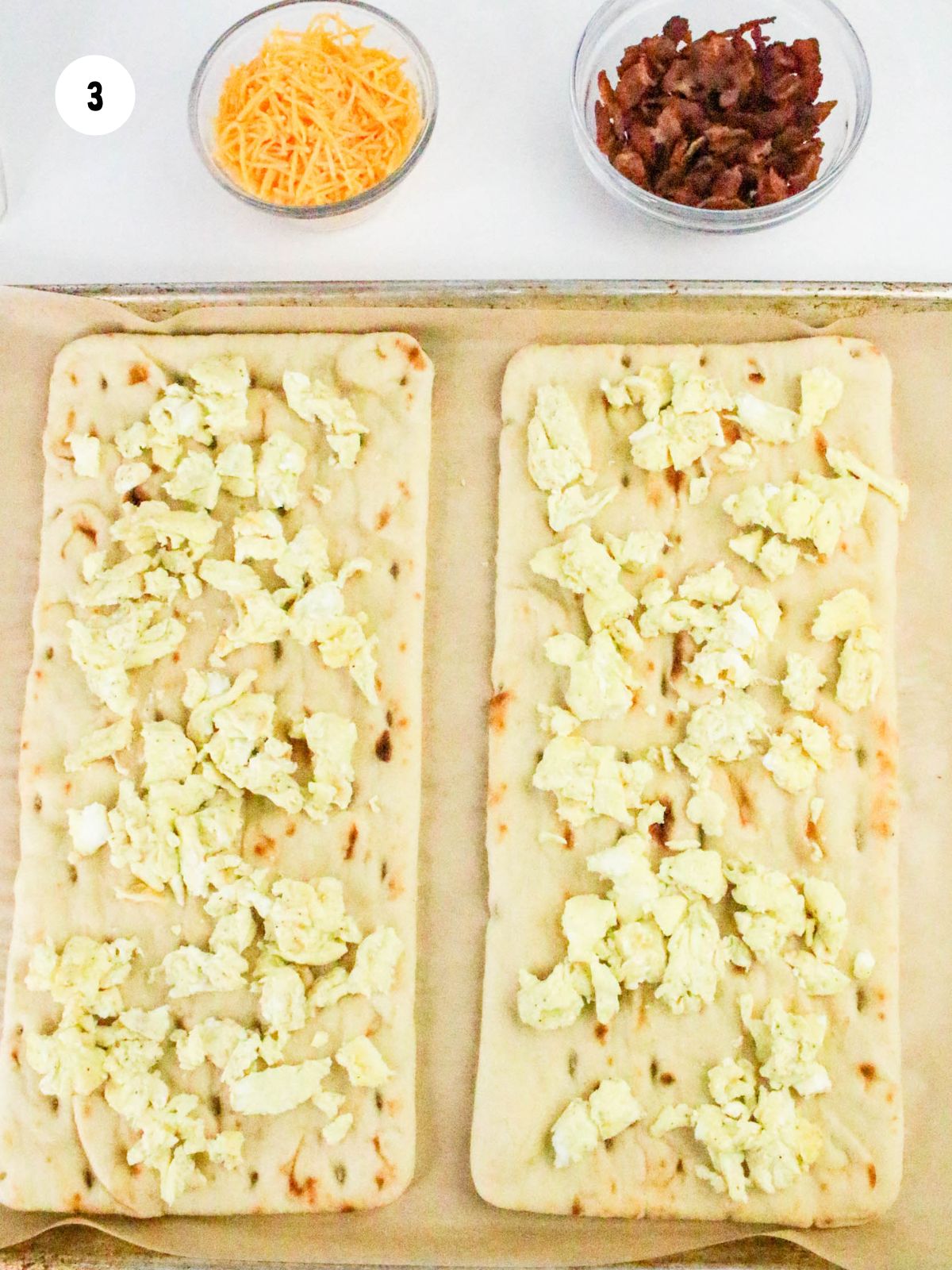 Scrambled eggs placed on 2 rectangle flatbreads.