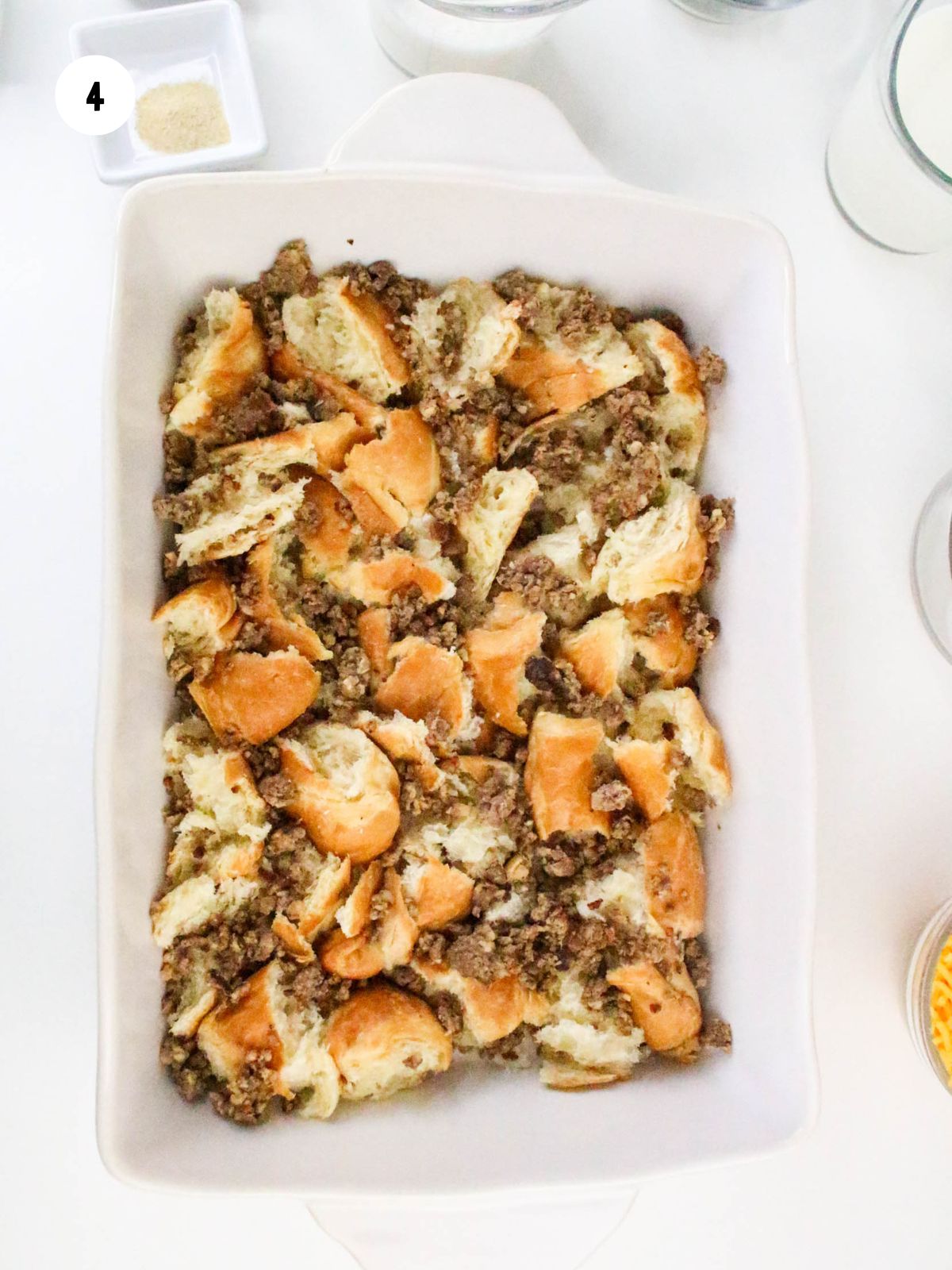 Cooked crumbled sausage added on top of the croissant pieces.