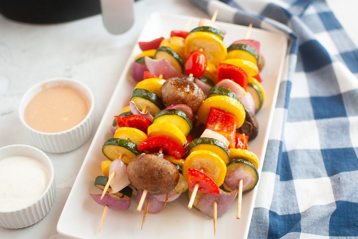 White rectangle platter filled with colorful vegetables on skewers.