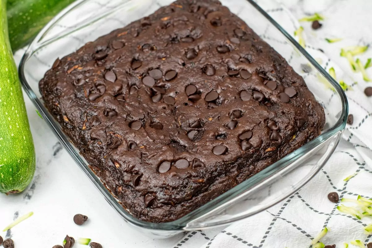 Chocolate chocolate chip zucchini cake in a square baking dish.