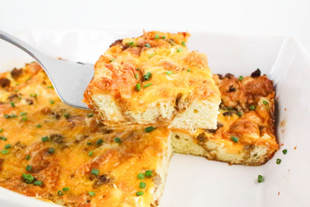 Slice of Croissant Breakfast Casserole lifted out of the pan on a spatula.