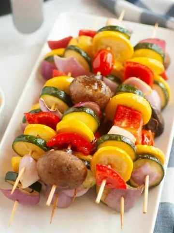 Vegetable kabobs served on a white rectangle platter.
