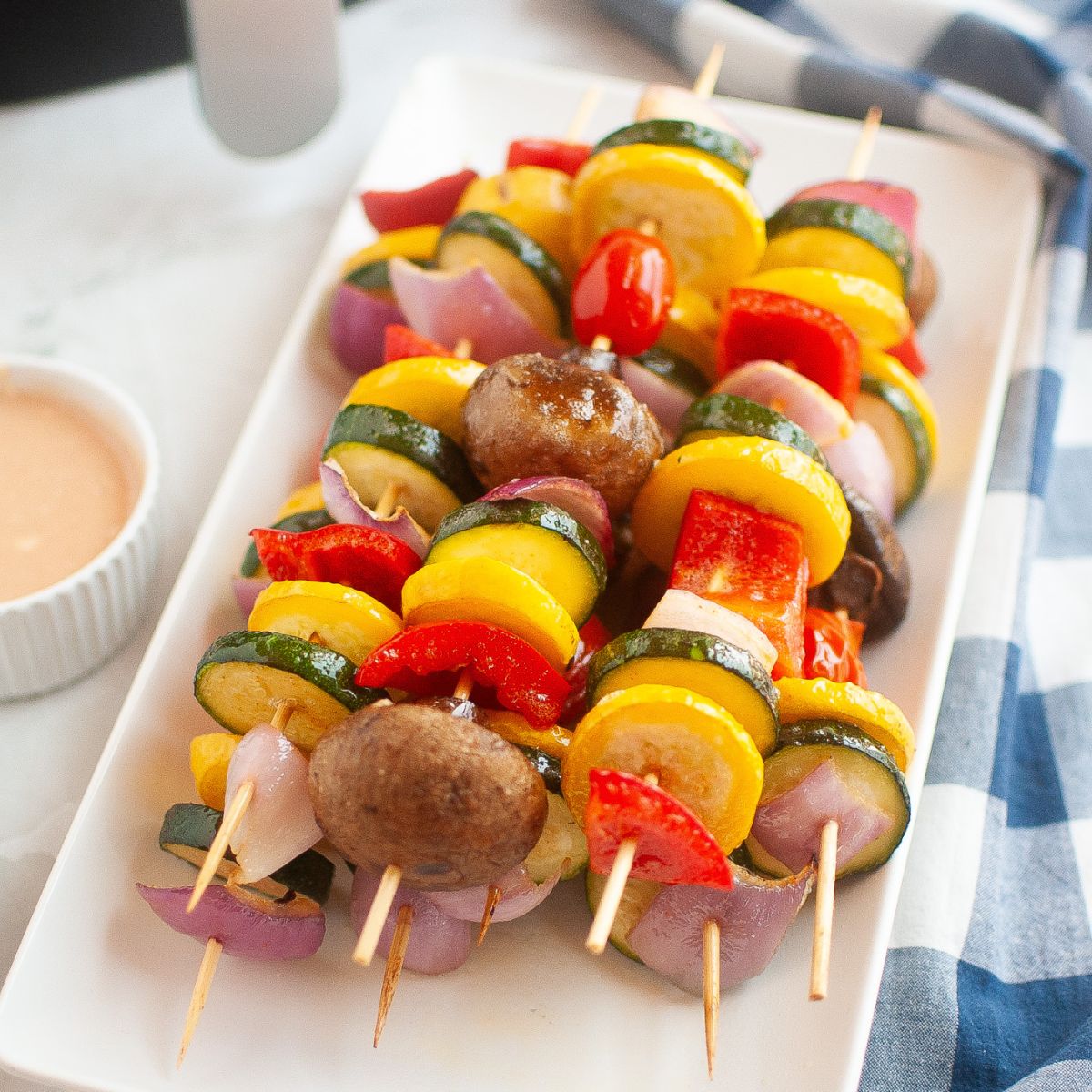 Vegetable kabobs served on a white rectangle platter.