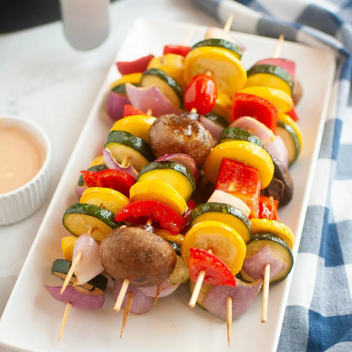 Vegetable kabobs served on a white rectangle platter.