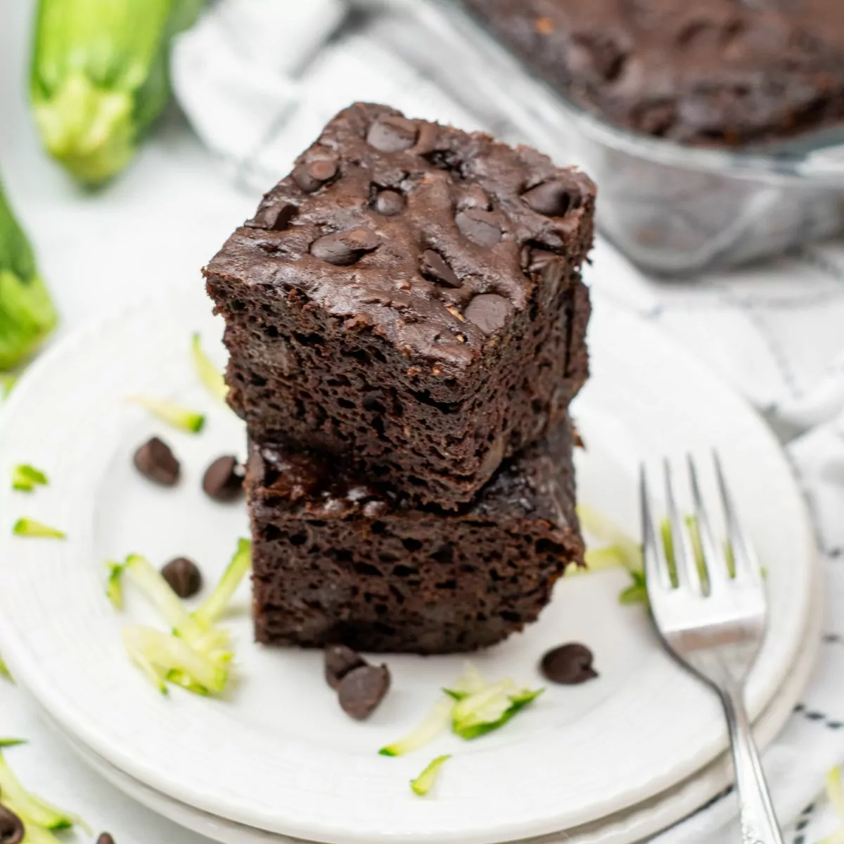 Two slices of chocolate zucchini cake stacked on a white plate.