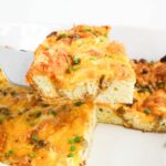 Slice of Croissant Breakfast Casserole lifted out of the pan on a spatula.