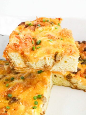 Slice of Croissant Breakfast Casserole lifted out of the pan on a spatula.
