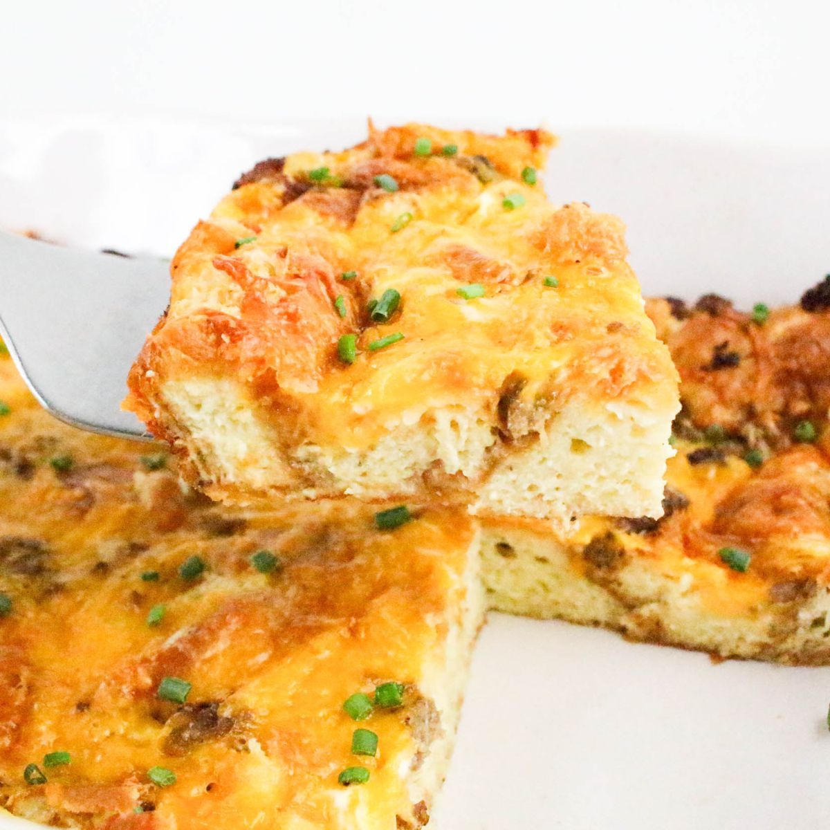 Slice of Croissant Breakfast Casserole lifted out of the pan on a spatula.