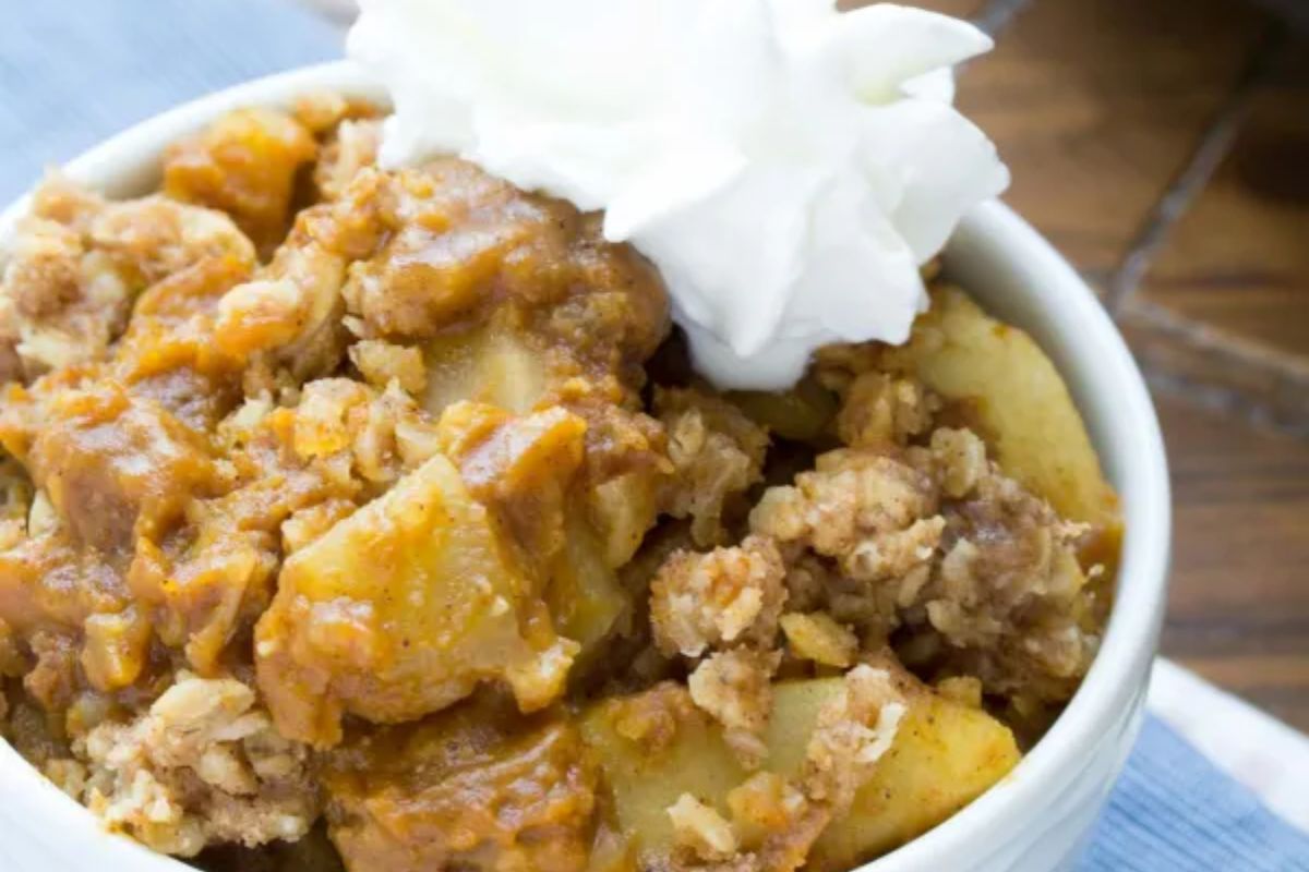 bowl of Pumpkin Apple Crisp with whip cream on top