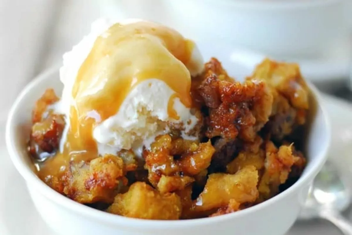 a bowl of Pumpkin Pecan Bread Pudding with ice cream and caramel syrup on top
