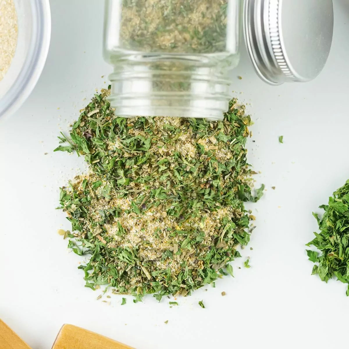 dried seasoning mix spilling out of a glass bottle on white surface.