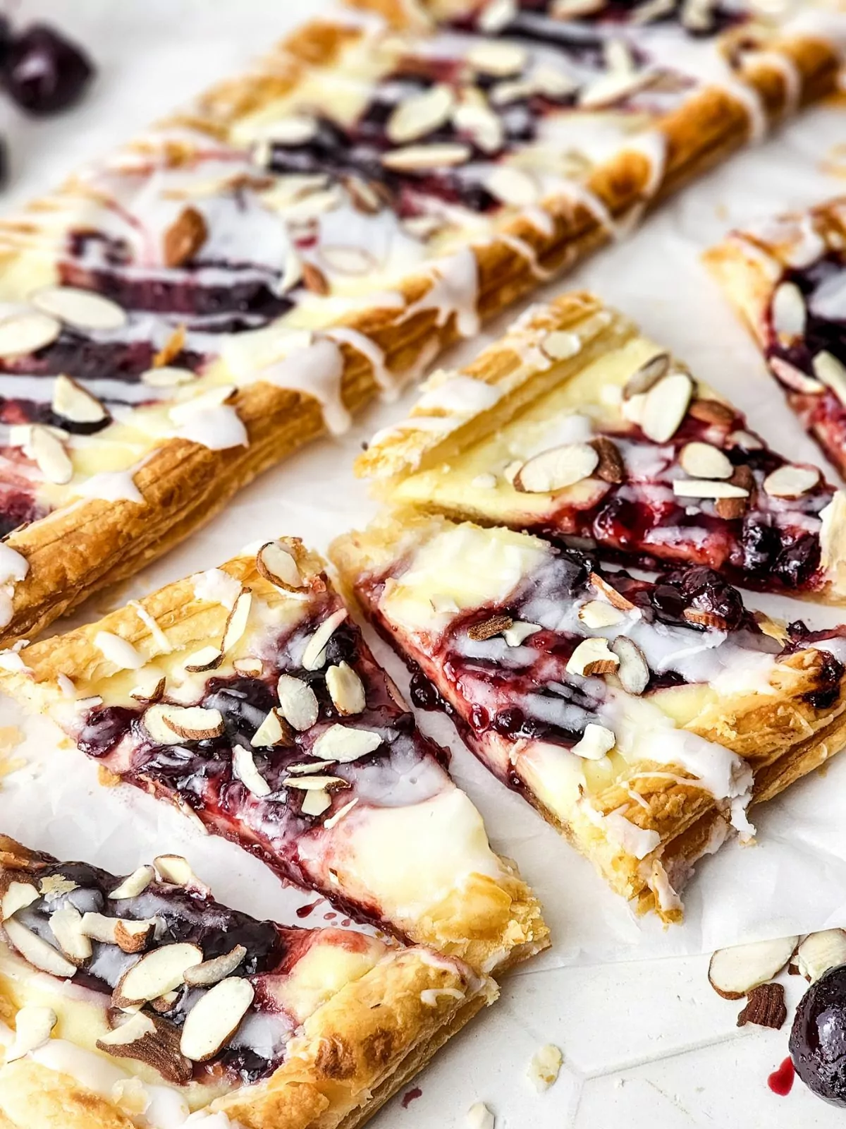 Puff pastry blueberry danish topped with glaze and sliced almonds.
