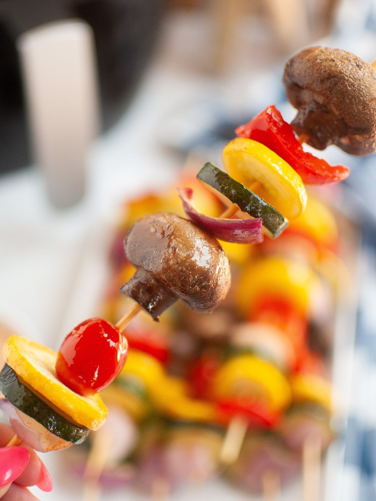 Hand holding a skewer of air fried vegetables.