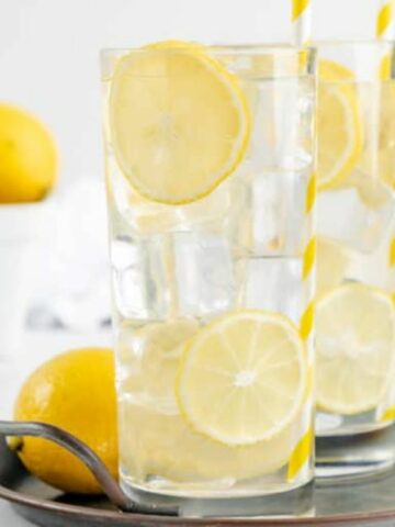 2 glasses of lemonade on tray with fresh lemons.