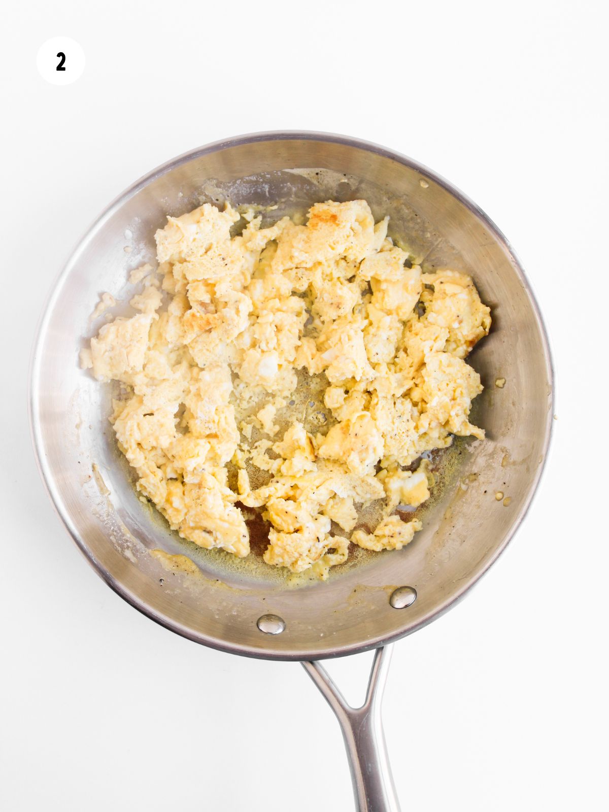 scrambled eggs in a stainless steel pan.