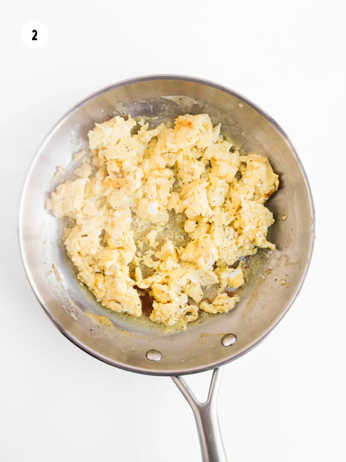 scrambled eggs in a stainless steel pan.