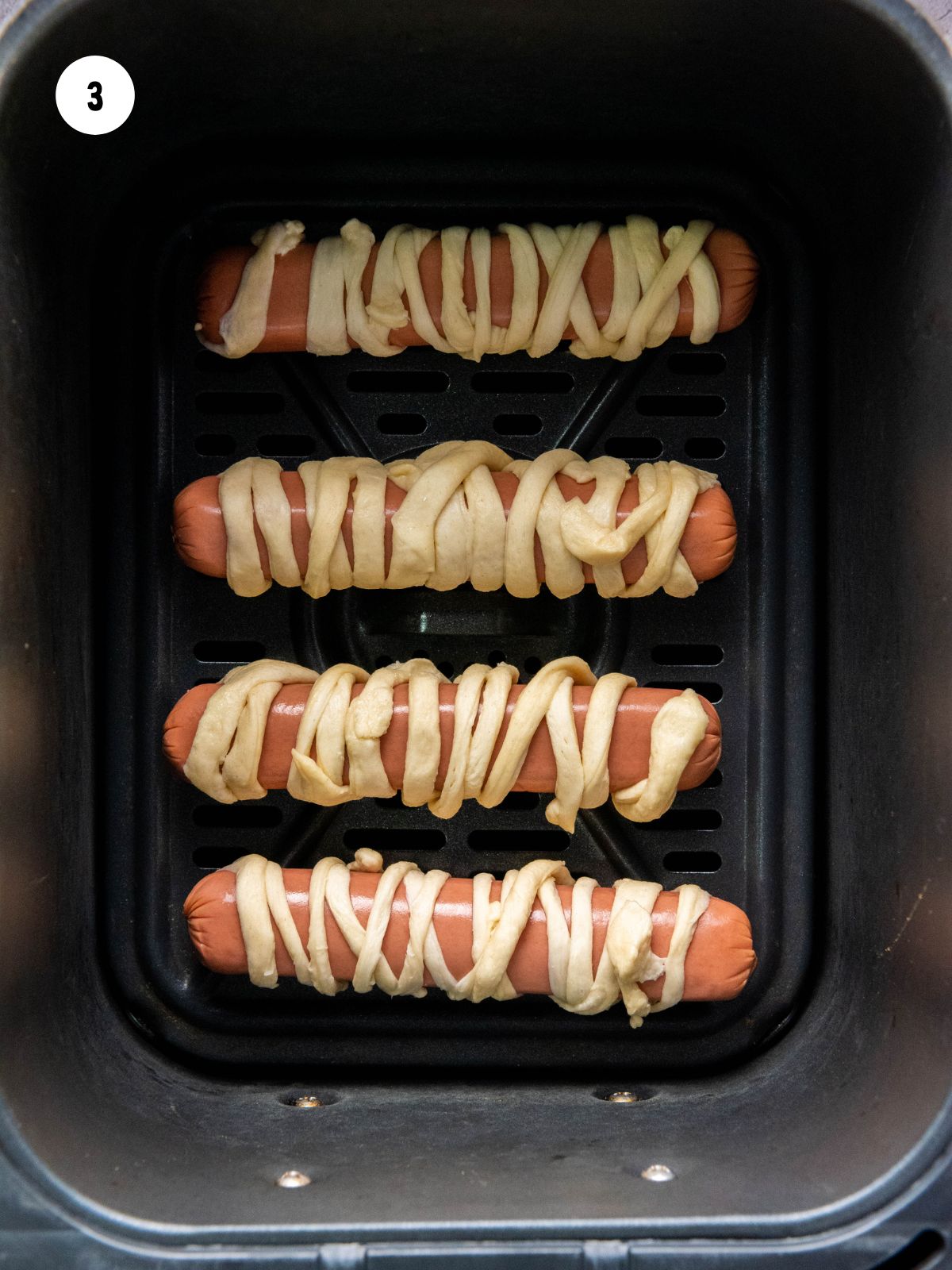 Wrapped hot dogs in air fryer basket.