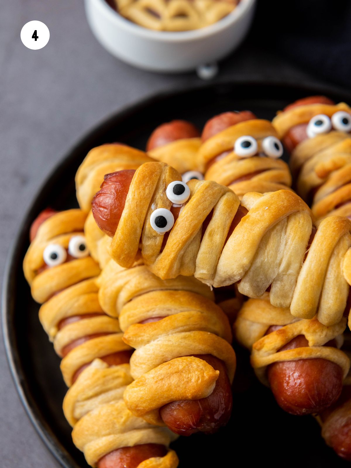 Cooked crescent roll hot dogs with edible eyes added.