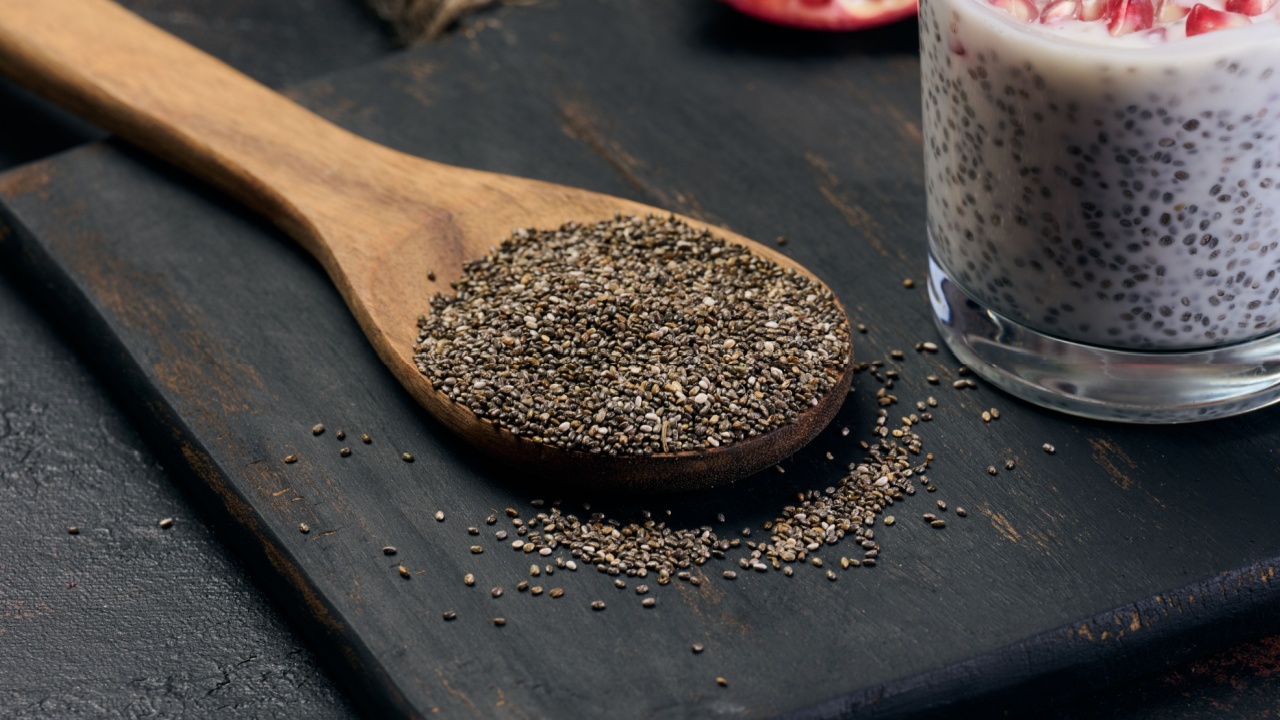 Chia seeds in a wooden spoon on a black table, close up