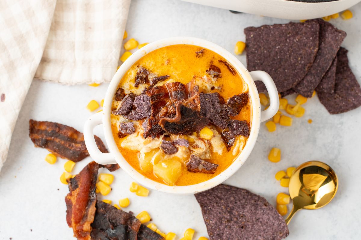 Bowl of Chicken Corn Chowder topped with bacon pieces and tortilla chips.