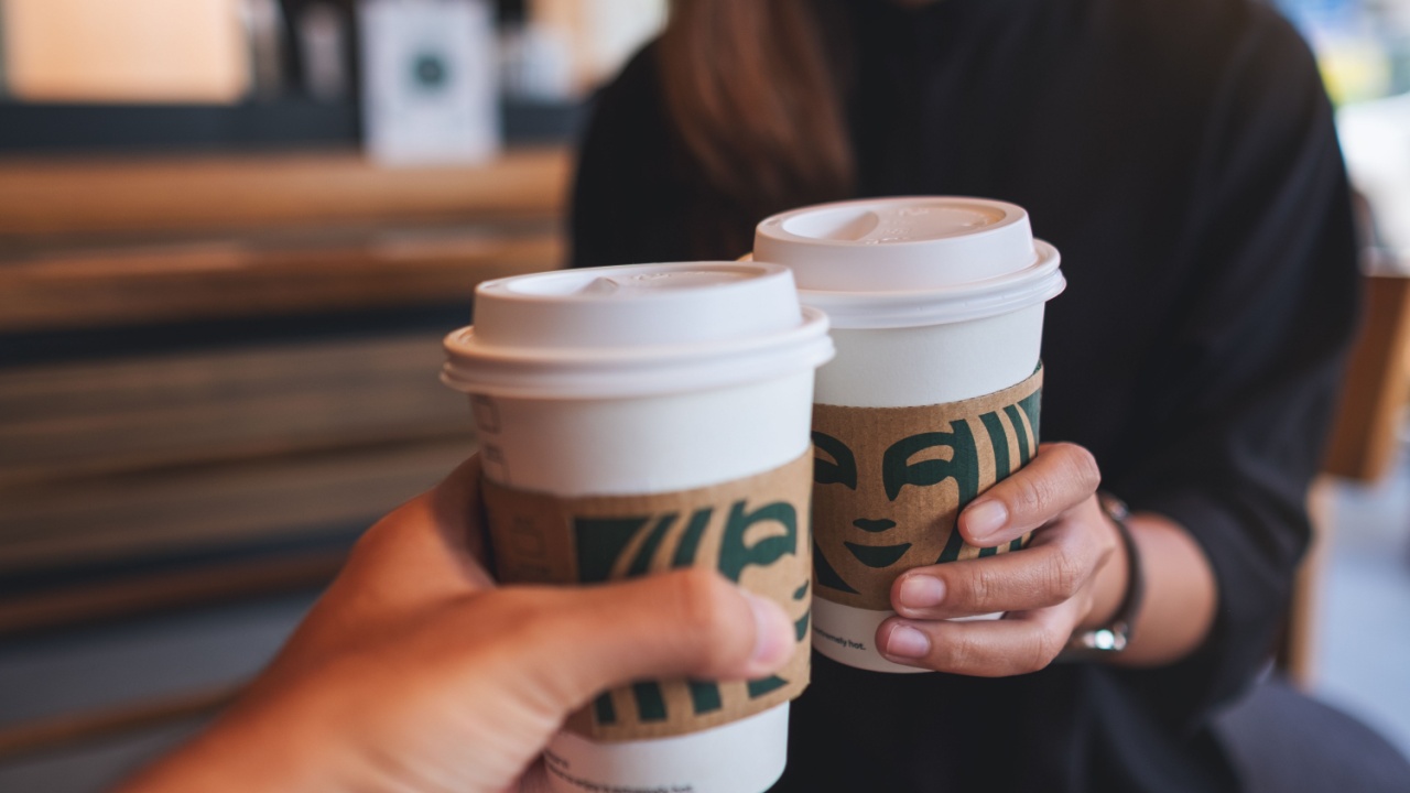 Closeup of a couple people holding and clinking two cup of hot coffee at Starbucks coffee shop