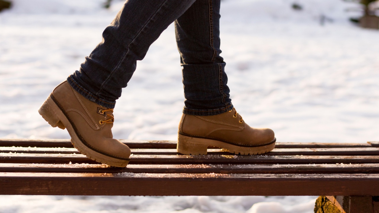 Closeup woman's legs standing on bench in beige boots and blue jeans on blurred winter sunny day background