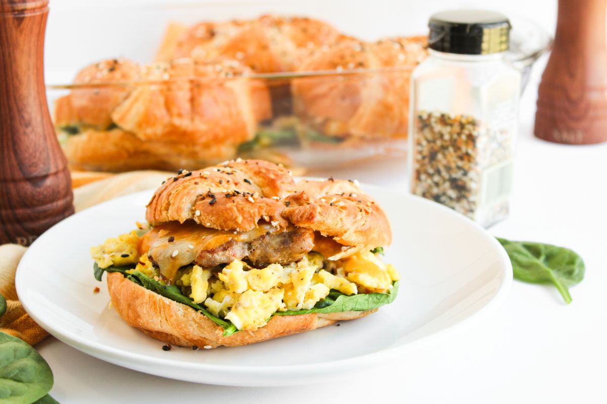 Sausage, egg, and cheese croissant sandwich with fresh spinach.