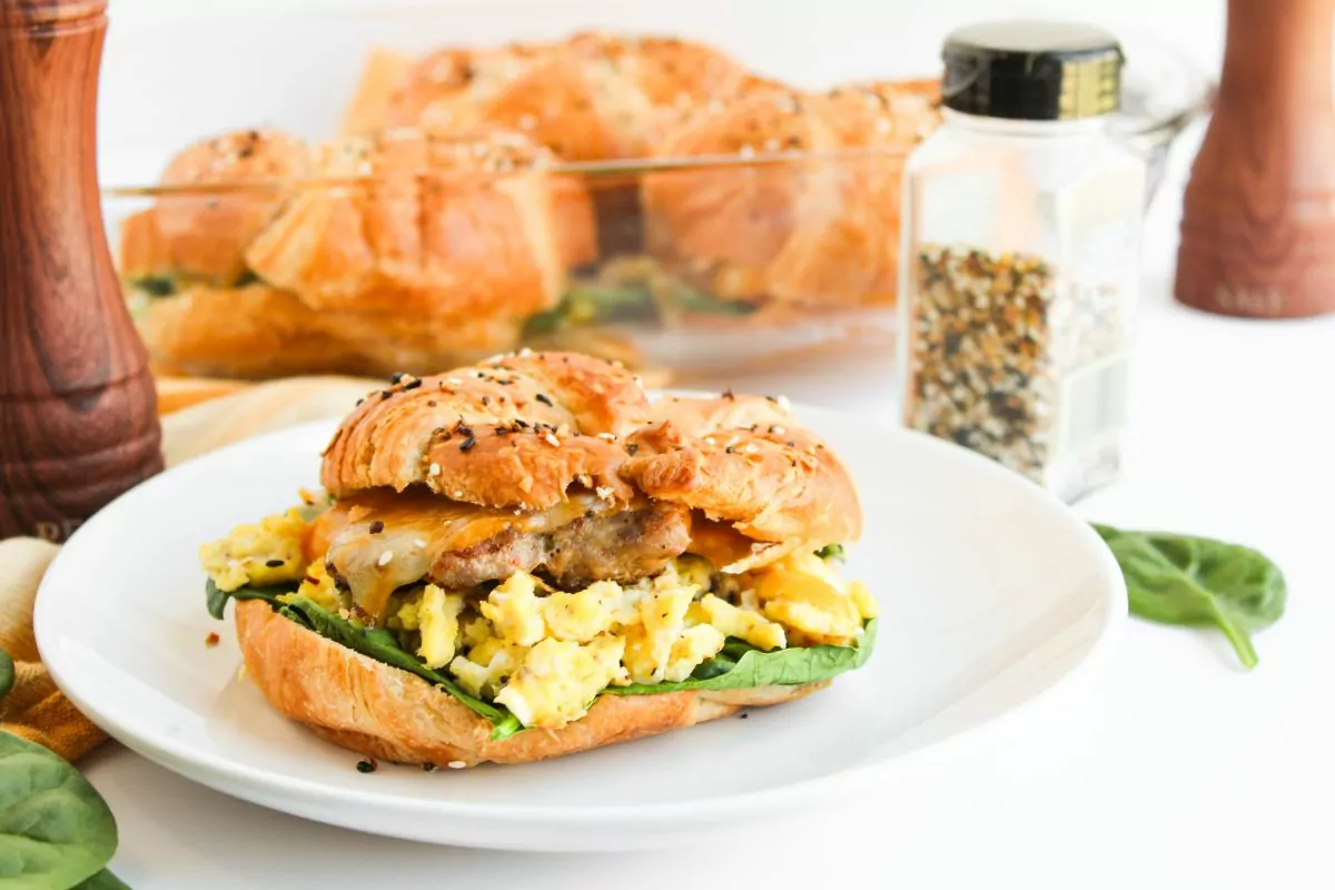 Sausage, egg, and cheese croissant sandwich with fresh spinach.