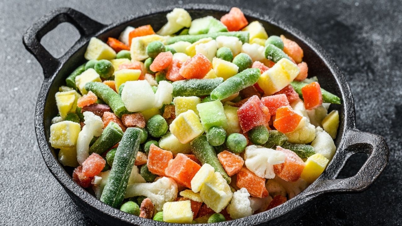 Frozen raw vegetables in a pan. Vegetarianism. Black background. Top view