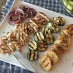 grilled chicken with grilled veggies on white tray.