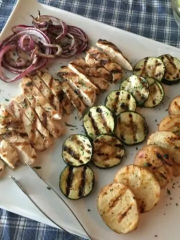 grilled chicken with grilled veggies on white tray.