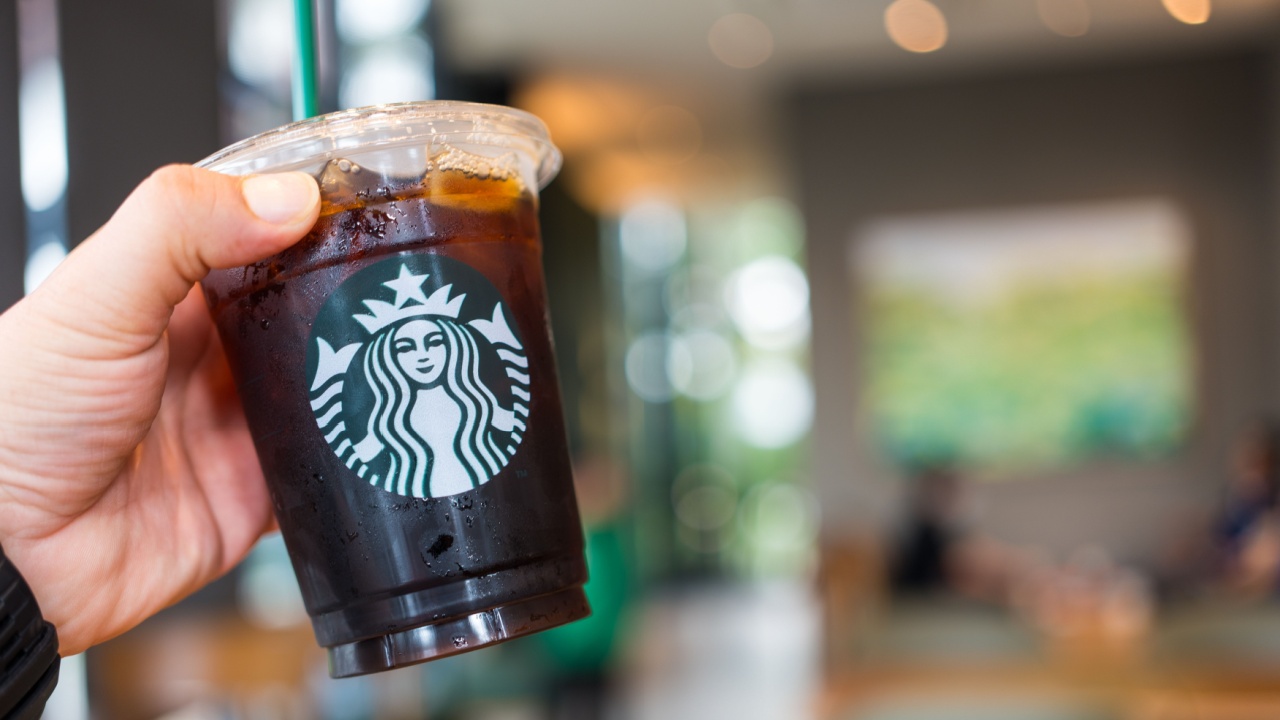 Man holding a Starbucks cold brew beverage cup in hand at Starbucks shop