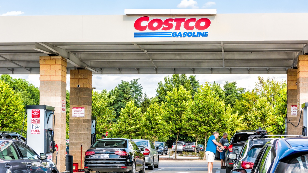People in cars waiting in long lines to fill up vehicles with gas at Costco store in Virginia with man holding nozzle