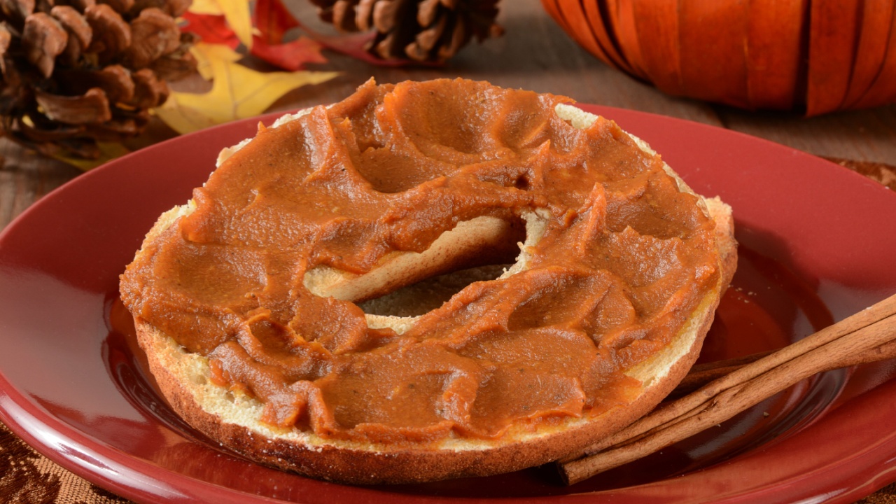 Pumpkin butter spread on a cinnamon bagel with cinnamon sticks